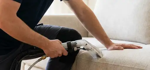 Professional upholstery cleaner deep-cleaning a fabric sofa with a handheld extraction tool, Long Beach, CA.